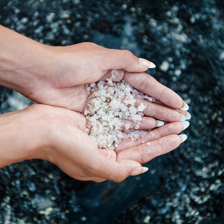 Open hands holding loose crystals of hawaiian sea salt