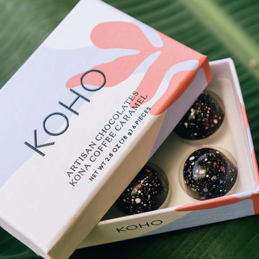 Box of KOHO chocolates with the lid open to reveal colorful bon bons inside